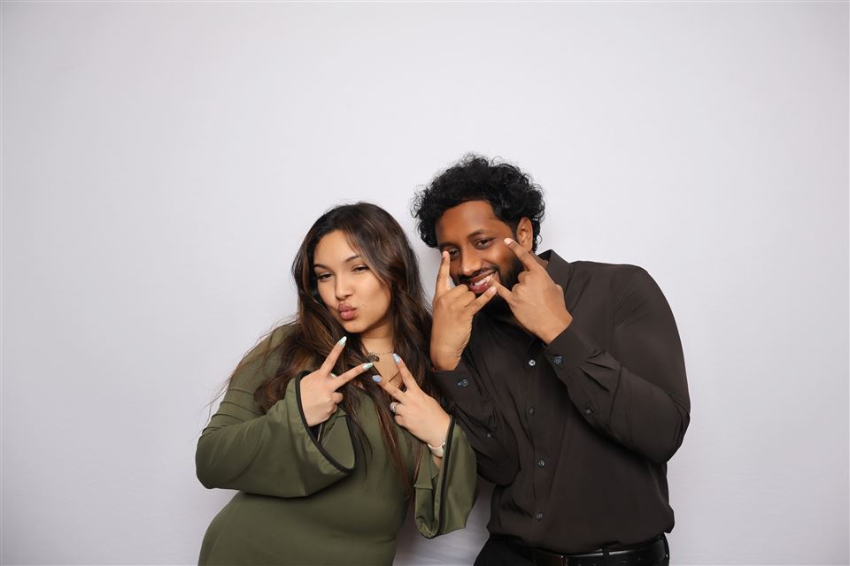 Two event guests make playful hand signs in an open-air photo booth