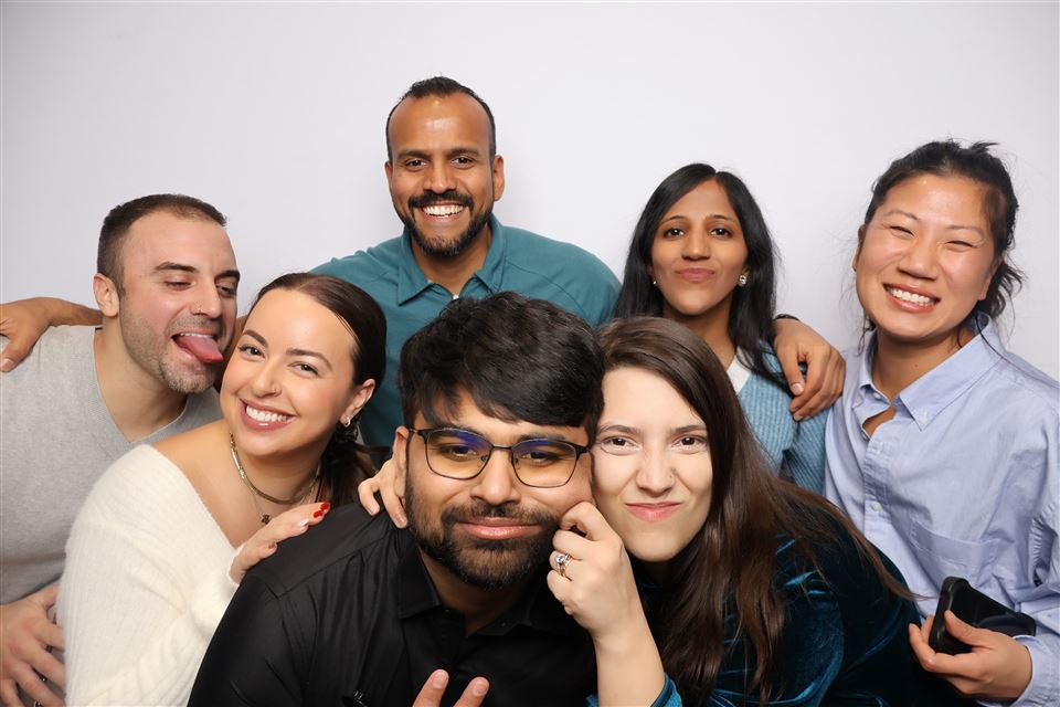 Seven event guests crowd together and make playful faces for a photo booth portrait